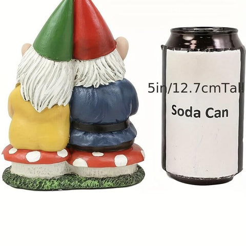 Garden gnome couple statue sitting on mushrooms next to a soda can for size comparison.